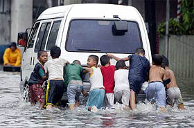 Children push a van that broke down in the middle of a flooded street