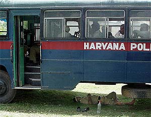 A policeman rests under a bus