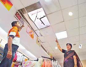 An employee of Ebony shows the false ceiling broken by thieves to enter the shopping arcade