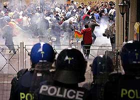 Anti-G-8 demonstrators run away as the riot police fire concussion and tear gas grenades