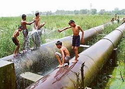 Children enjoy the fountain of water from a leaking pipeline of the Kajauli waterworks near Maloya village.