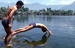 Youths jump into the Dal Lake to to beat the heat