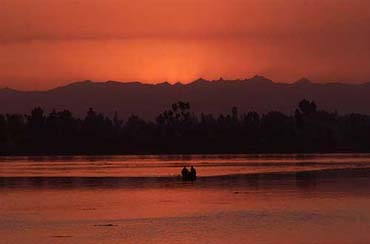 Kashmiris row a boat as the sun sets over Dal Lake