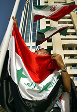 A worker raises the Iraqi flag next to Iranian and Kuwaiti flags in Doha for the OPEC summit
