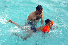 A boy enjoys a bath with his father in a swimming pool in Ambala