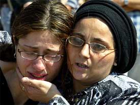 A mourner wipes the face of the grand-daughter of suicide-bomb victim Martin Tita during his funeral 