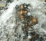 A boy cools himself with water leaking from a pipe in Kolkata 