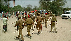 Policemen try to disperse a crowd in Dhobiana locality during a demolition drive