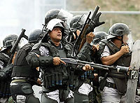 Venezuelan metropolitan policemen huddle while confronting rioters in Caracas