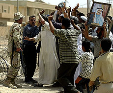 Iraqi protesters crowd a US Army soldier