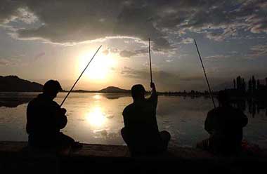 Tourists enjoy fishing as the sun sets over the world famous Dal lake