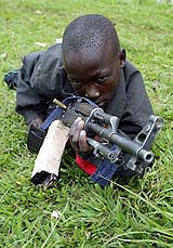 A child soldier practices with a machine gun