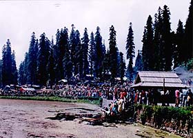Devotees throw coins, notes and ornaments into the Kamrunag Lake