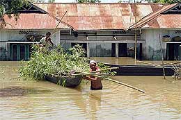 Flood victims carry food and bamboo on a boat