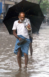 An elderly man walks down a flooded street