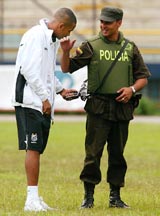 Brazilian soccer star Robson de Souza of Santos club touches the machinegun of a Colombian policeman