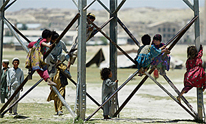 Afghan children play at the base of an electricity transmission tower in Kabul 