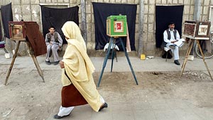 An Afghan woman walks past photographers, sitting with their vintage cameras