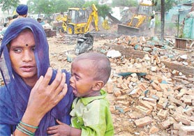 Rendered homeless: A woman stands near the debris of her jhuggi while a demolition drive goes on at Shaheed Bhagat Singh Colony, Sector 49, Chandigarh