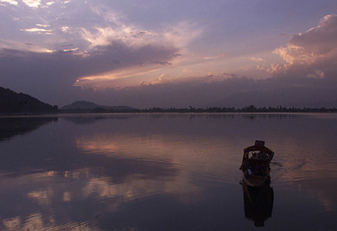A Kashmiri rows a boat as the sun sets over Dal Lake