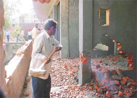 A worker deployed by an MC demolition team hammers down a wall of a shop in the commercial complex being constructed