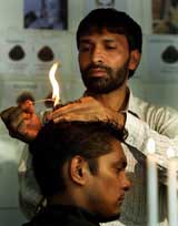 Indian hairstylist Aqueel Kiratpuri uses a candle flame to give a porcupine look to a customer