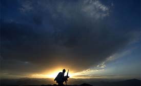 An Afghan soldier keeps watch from atop a strategic hilltop