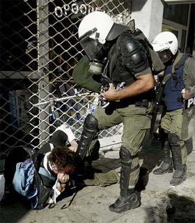 A Greek riot policeman kicks a protester