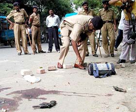 Blood stains and pistols seen on a street as a policeman examines the spot in Ahmedabad