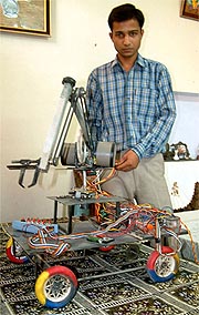 Raman Garg, an engineering student, poses along side a robot that he made along with eight other students