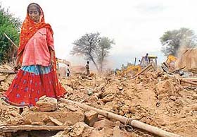A woman searches her belongings from her demolished house at Peer Colony, Palsora