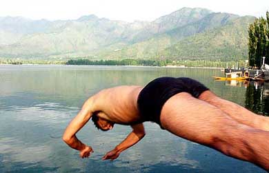 A youth dives into the  Dal Lake to beat the heat and enjoy a swim