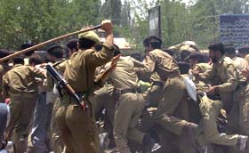A policeman wields his stick to disperse Home Guards personnel