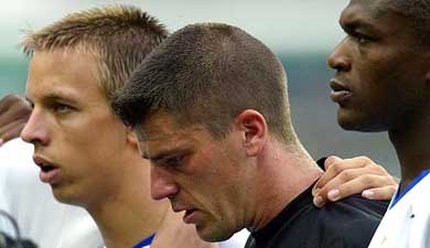 France's goalkeeper Gregory Coupet stands in silence with teammates Benoit Pedretti and captain Marcel Desailly in memory of Marc-Vivien Foe of Cameroon