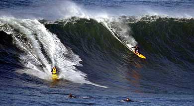 Victor Levett drives a jet-ski as his tow-in partner Jason Garland slides down the face of a large wave