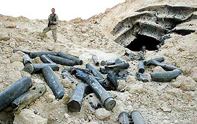 A US Army soldier examines ammunition cases at an Iraqi warehouse in the desert near Haditha