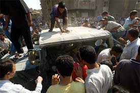 Iraqi men tear apart a US Army vehicle after it was hit by a rocket-propelled grenade in Baghdad