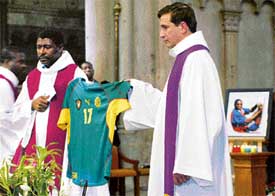 Cameroon and French priests hold the shirt of late Cameroon footballer Marc-Vivien Foe during his funeral service