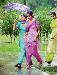 Students open umbrellas as the rain hit Ludhiana on Saturday