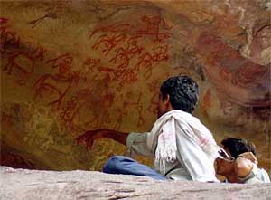 A man points to a pre-historic cave painting in Bhimbetka