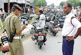 Traffic police personnel challan a wrongly parked vehicle on a road in front of the demolished furniture market on the SAS Nagar-Chandigarh border
