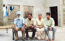Indian hockey team goalkeeper Kanwaldeep Singh with his parents and younger brother in front of his dilapidated house at Beer Ahmedabad village, near Ludhiana, on Sunday. 