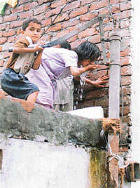 Despite the outbreak of the disease, children drink water from a hand pump