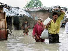 Flood victims carry their belongings through their flooded neighborhood in Silguri, some 600 km north of Kolkata