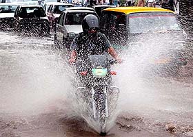 A motorcyclist wade through the  waterlogged street 