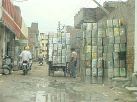 Tin boxes outside a tin recycling factory encroach upon a road in Hira Nagar on the Kakowal road