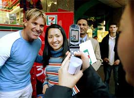 Shane Warne poses with a fan as others queue for his autograph