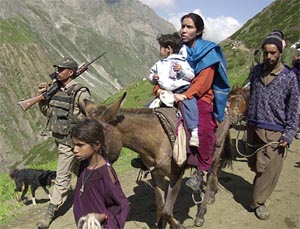A BSF soldier keeps guard as pilgrims pass by