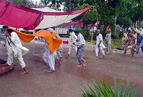 Akali workers rush for shelter as it begins to rain during a party meeting at Alamgir