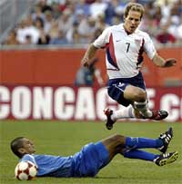 USA's Eddie Lewis jumps over El Salvador's Victor Manuel Velasquez 